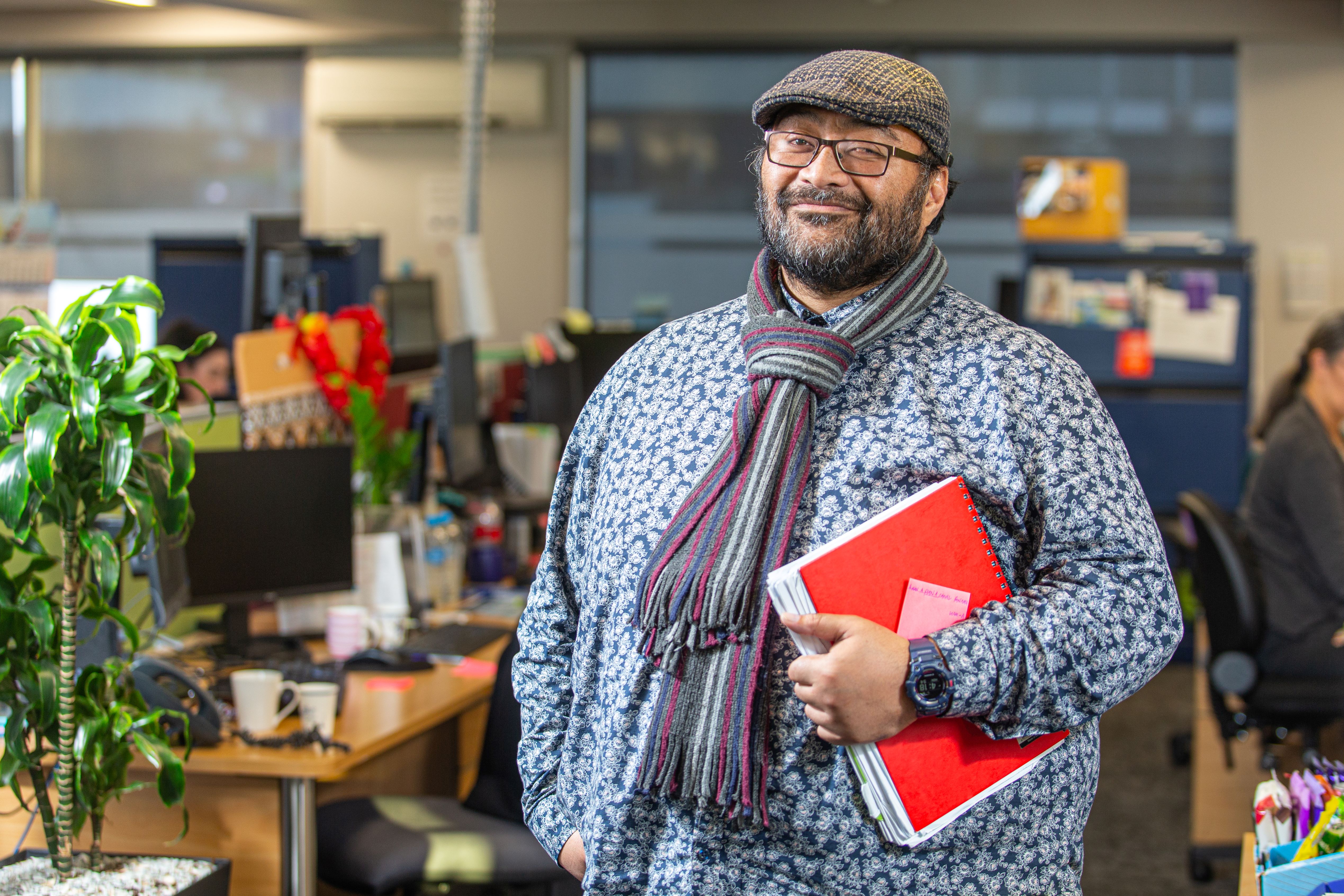 Staff member stands in Community Corrections Office holding a large binder of notes 